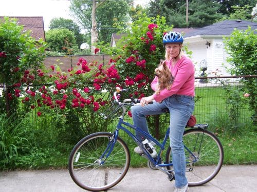 Ann holding her dog on her bike