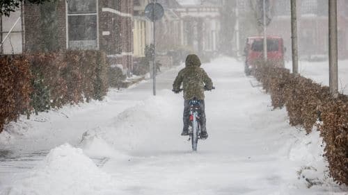 person biking in the snow with layers of clothing