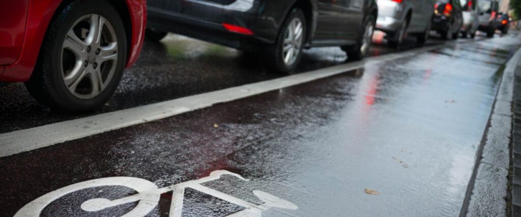 Painted bike lane on urban road next to parked cars illustrating door zone risk covered in bike lane markings guide