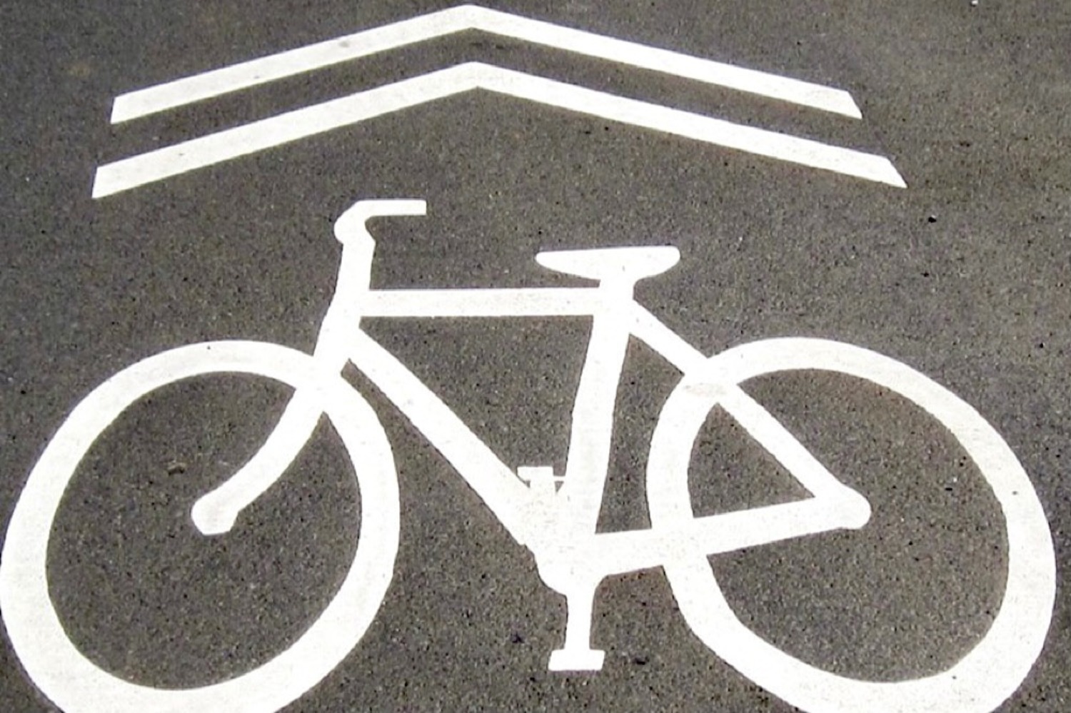 White sharrow shared lane marking painted on road surface indicating shared space for bike lane markings guidance